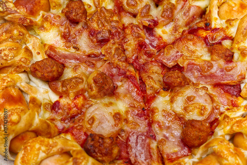 Extreme close-up of pizza toppings featuring melted cheese, crispy bacon, and meatballs on a sausage-stuffed crust pizza