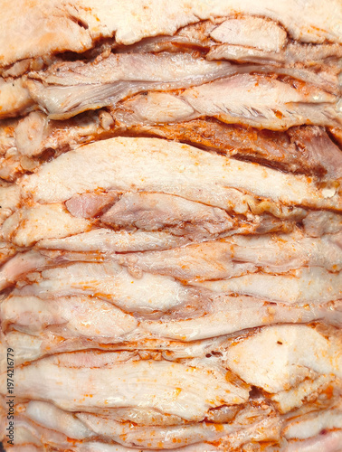 Extreme close-up of seasoned chicken or lamb meat stacked on a vertical rotisserie for Doner Kebab, showing the juicy and flavorful texture