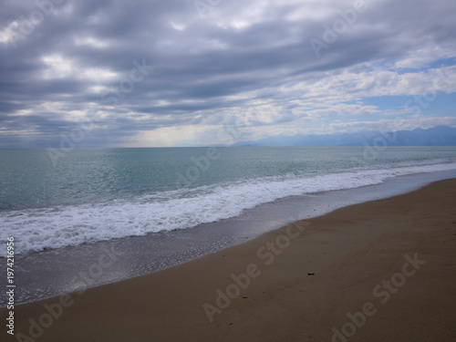 beautiful sandy shore with calm blue water on a cloudy day