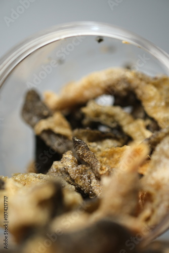 Fried salmon fish skin snacks in a clear plastic container.