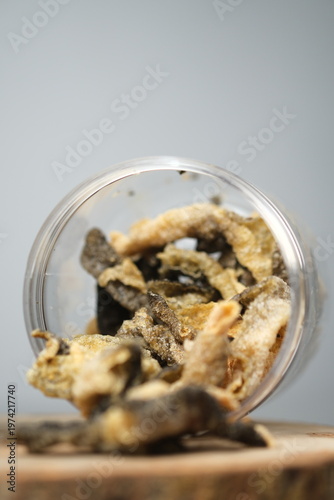 Fried salmon fish skin snacks in a clear plastic container.