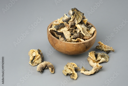 Wooden bowl showcases crispy salmon skin chips on gray surface. Perfect for food blogs, menus, snack packaging, culinary websites.