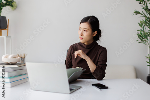 Vászonkép Asian woman working from home thinking about business strategy