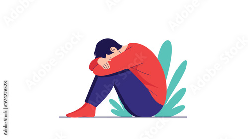 Sad man sitting alone on the floor and hugging his knees tightly in a moment of deep despair, loneliness, or depression.