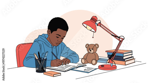 Focused young boy sitting at his desk at home and writing in his notebook by the light of a red desk lamp, with books and a teddy bear nearby.