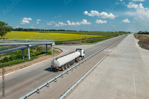 Aerial view of a tanker truck on highway with colorful fields around
