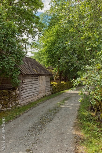 Moss-coverd stone walls along narrow gravel path in summer, Koguva village, Muhu, Estonia, Europe.