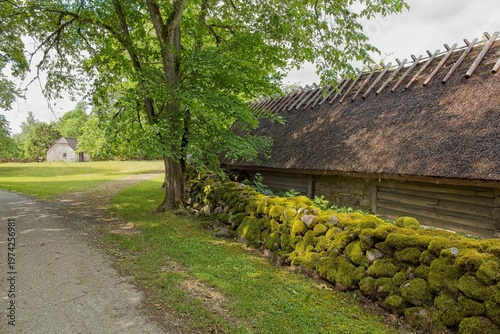 Moss-coverd stone walls along narrow gravel path in summer, Koguva village, Muhu, Estonia, Europe.