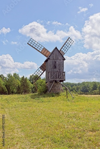 Typical Estonian post windmill standing in a lush green field in summer with clouds in the sky, Muhu, Estonia, Europe.