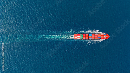 Aerial top view of cargo ship runing on sea close warehouse harbor.