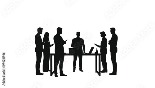 Business professionals stand around a table with laptops, engaging in a productive discussion or informal.