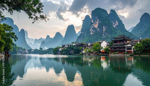 A breathtaking panoramic view of Guilin's karst mountains and traditional architecture reflected in the tranquil waters of Li River, showcasing the stunning natural beauty of southern China.