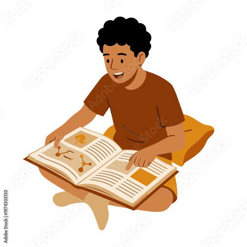 A boy sits cross-legged reading an open book with a smile on his face.