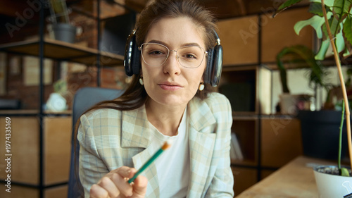 Woman with headphones pointing and explaining during online coaching session. Concept of instruction, guidance, remote learning, business coaching, and communication.