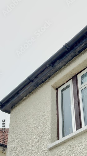 Vertical video social media - Water leaking from an overflow pipe at the base of a property roof, caused by the water supply failing to properly shut off when the internal loft storage tank is full.