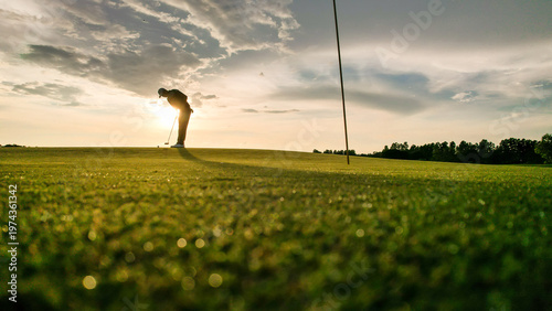Professional young male golfer swings his club on scenic golf course. 