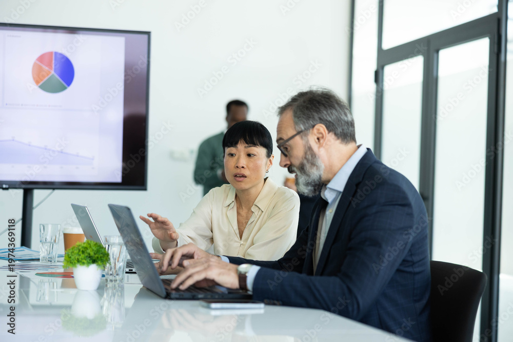 Fototapeta premium Diverse business people discussing data analysis, working on strategy in a modern conference room, promoting teamwork and communication