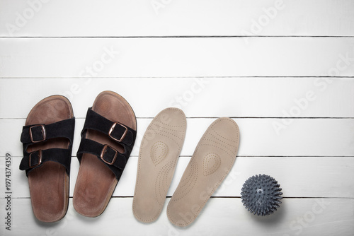 Top view of orthopedic slippers, insoles and gray massage ball with copy space