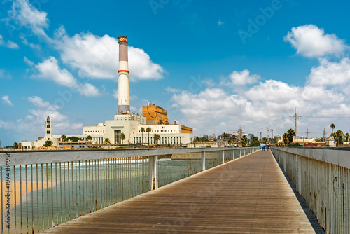 Boardwalk leading to the Reading power station under blue sky with white clouds in Tel Aviv, Israel.