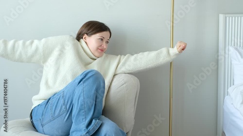 A woman in a white sweater sits on chair and stretches, relaxation concept.