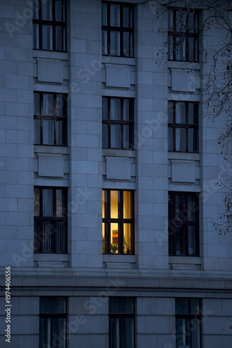 Fotografie Fragment of a classic building facade at dusk with one brightly lit window among dark ones