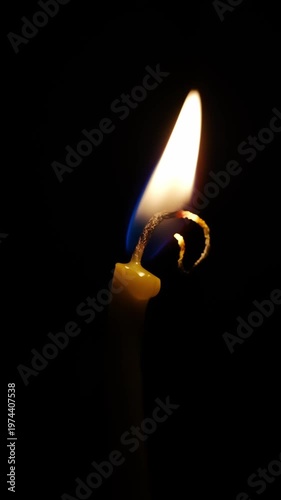 Capturing the glow of a burning candle at night with soft wax dripping and flame flickering in a dark space