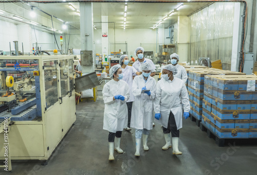 diverse team quality control specialist wearing protective coat mask collaborate digital tablet in modern food processing factory representing standard technology teamwork inclusive multicultural work