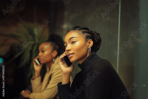 Two women working in a call center, wearing headsets and communicating with clients in a modern office environment.