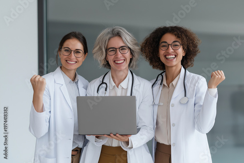 Three female doctors in a modern medical office, standing together and smiling, holding a notebook during a professional discussion.