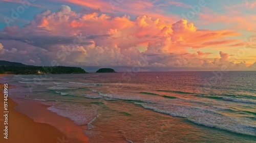 Aerial view of A breathtaking view of the sun setting over the ocean, casting warm golden hues across the waves and clouds while people enjoy the tranquil shoreline. Poo island Kata beach Phuket