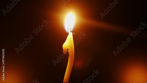 Candle burns brightly in a dark space, showing the steady flame and melting wax over time at a night gathering