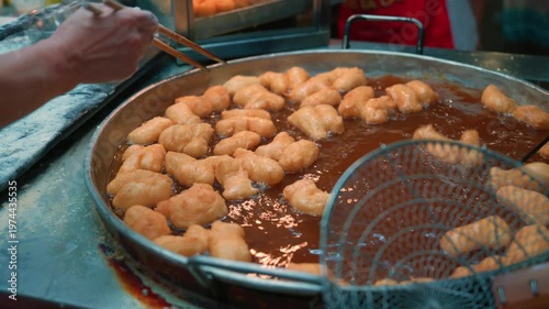 Close-up of a street food vendor deep frying traditional Pa Thong Ko or Chinese donuts in a large wok of hot oil