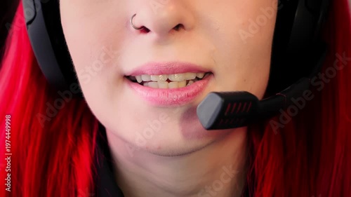 Closeup view of female speaker using high quality microphone for clear communication. Mouth of Caucasian lady with headset showing nose piercing and red hair talks with warm tone and clear diction