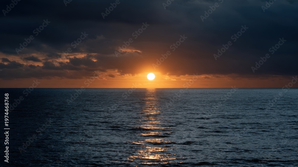 Fototapeta premium Sunset over calm ocean waters with dark clouds and golden reflections creating a serene coastal landscape at dusk, horizon visible in the distance