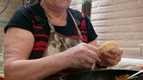 Elderly Woman Making Traditional Homemade Dumplings in a Rustic Kitchen Setting