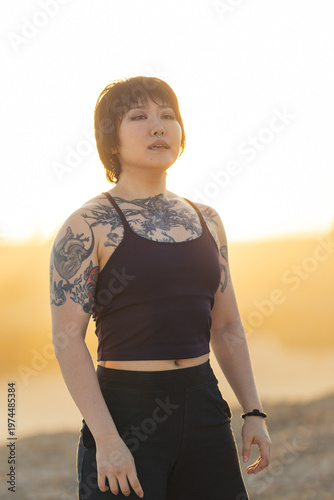 Confident asian woman with tattoos against sunset glow