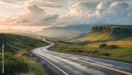 A winding asphalt road stretches through a vast, hilly landscape toward distant mountains under a dramatic, cloudy sky, illustrating travel, exploration, and the journey ahead in a rural setting.