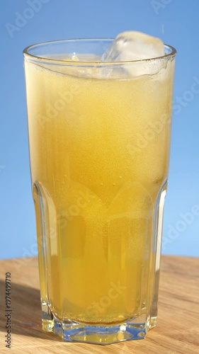 Ice cubes are thrown into a glass with healthy, flavored fresh sparkling kombucha. Iced fizzy drinks, and summer vibes.