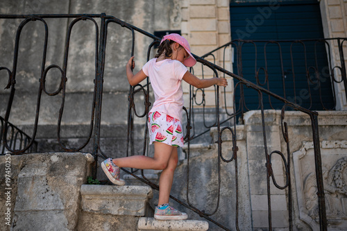 Girl on the stairs. A little girl walks down stone stairs. Vacation with a child. 