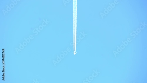 High-altitude commercial jet flying across a clear blue sky, leaving a long white contrail. Minimalist shot of aviation, travel, and atmospheric transport in bright daylight.