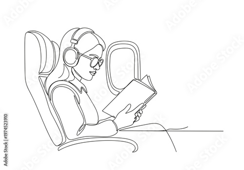 Female passenger reading book with headphones on airplane seat