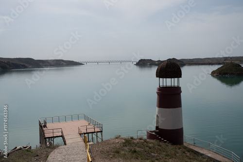 Solitary lighthouse on a pier surrounded by turquoise water. Qonayev, Central Asia
