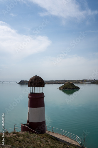 Solitary lighthouse on a pier surrounded by turquoise water. Qonayev, Central Asia