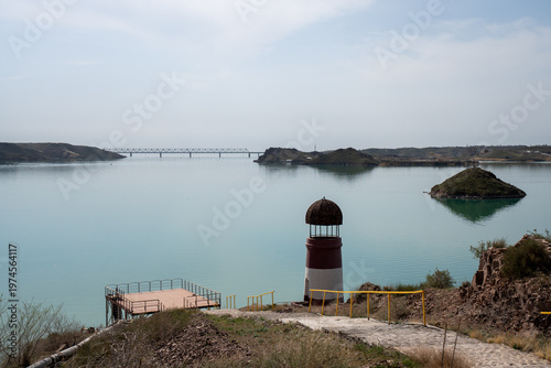 Solitary lighthouse on a pier surrounded by turquoise water. Qonayev, Central Asia