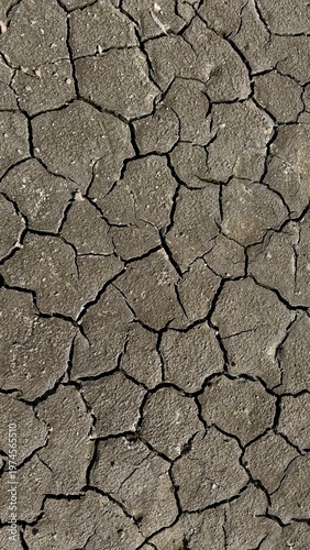 Dry cracked ground in vertical orientation creating abstract natural background. Symbol of drought, heat and climate change. High detail texture ideal for environmental and design projects.
