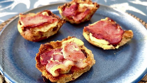 close up of blue plate with bacon strips and melted cheese on toasted bread buns