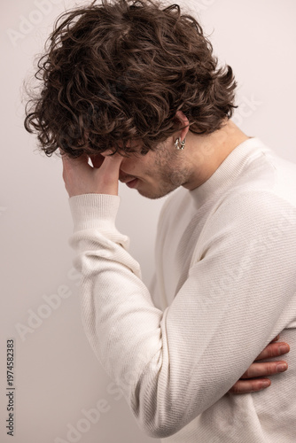 Portrait d’un jeune homme de 20 ans en proie au stress et à la réflexion, exprimant une tension intérieure et une fatigue mentale dans un cadre minimaliste