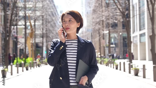 Japanese Businesswoman Walking and Talking on Phone in Spring City Street, Tracking Shot