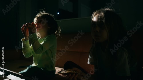 Two boys eating snacks on the sofa during a movie