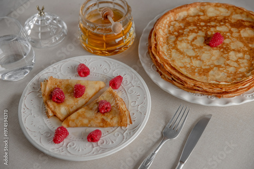 Crepes served with raspberries and honey jar. 